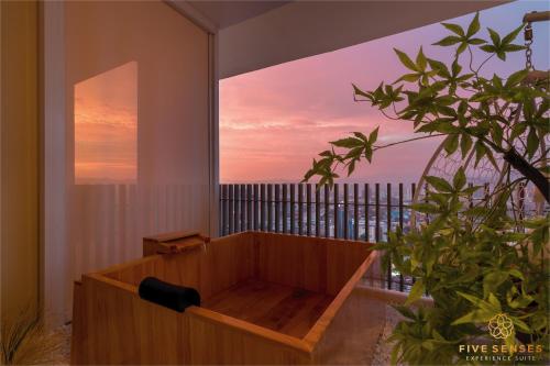 Cette chambre dispose d'une baignoire en bois et d'une fenêtre. dans l'établissement The Colony & The Luxe, Kuala Lumpur by Canopy Lives, à Kuala Lumpur