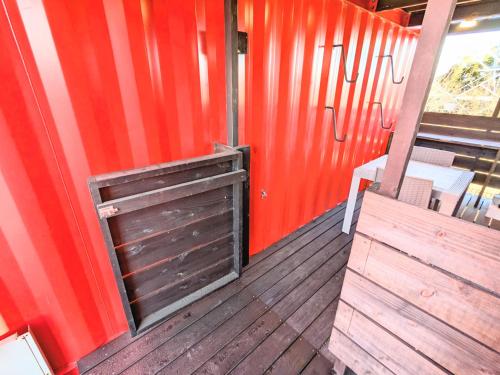a wooden porch with a wooden door and a red wall at Backshore 99 in Kujukuri