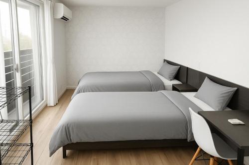 two beds in a room with a table and a desk at Backshore 99 in Kujukuri