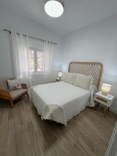 a white bedroom with a bed and a chair at Chalets Paraíso Playa de Mazagón Con Vistas al Mar in Mazagón