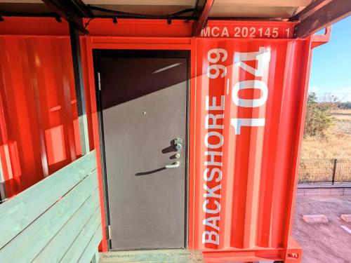 a door in a red building with a sign at Backshore 99 in Kujukuri