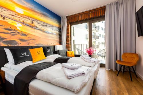 グダニスクにあるApartamentyGdansk eu - ŻURAWIE II - IIのベッドが2つあり、壁に絵が飾られた寝室