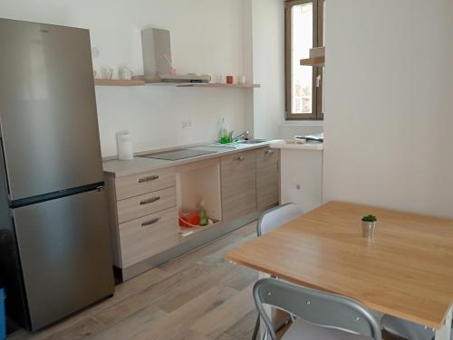 a kitchen with a wooden table and a refrigerator at Vi & Vi relax by the lake in Montorfano