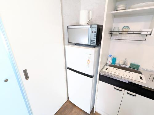 a small kitchen with a microwave and a refrigerator at Backshore 99 in Kujukuri