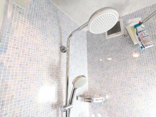 a shower in a bathroom with blue tiles at Backshore 99 in Kujukuri
