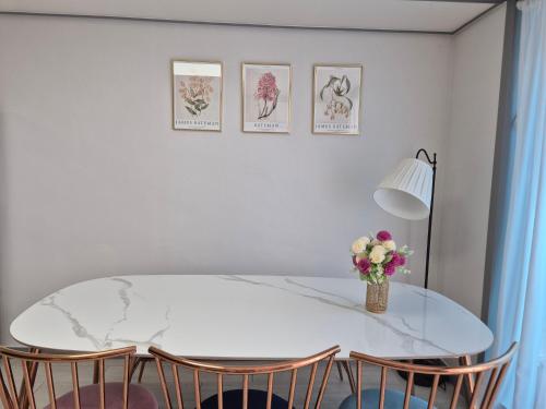a white dining room table with chairs and a vase of flowers at Eumm stay in Cheongju