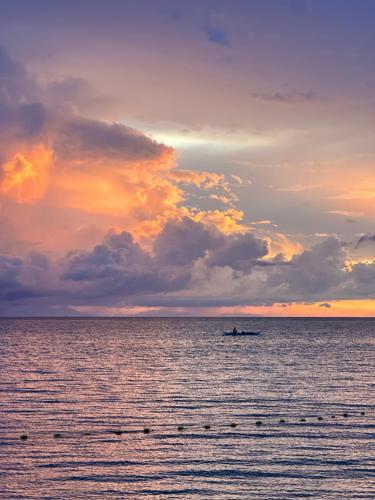 a boat in the middle of the ocean at sunset at Calilayan Cove Beach Resort 