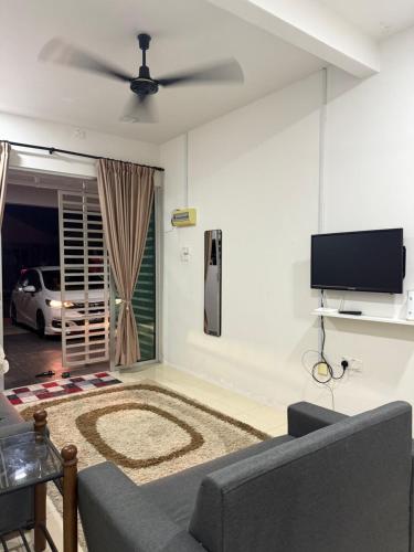 a living room with a couch and a flat screen tv at Cryptohouse Pantai Kelulut in Marang