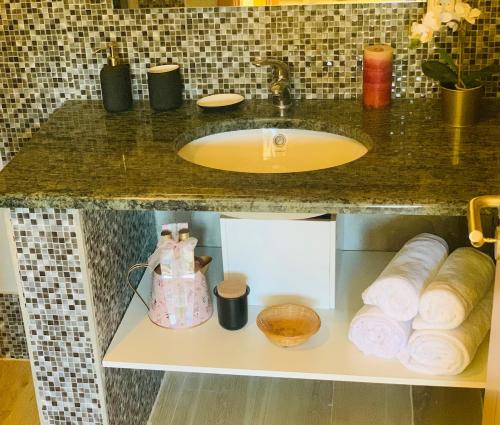a bathroom counter with a sink and rolls of towels at Oliveira's Little House in Caminha