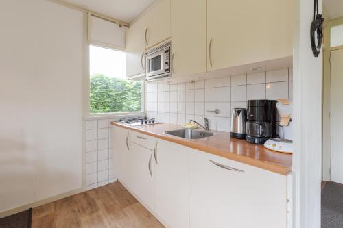 a kitchen with white cabinets and a sink and a window at Irina - Peaceful Holiday Home near Lauwersmeer National Park in Anjum