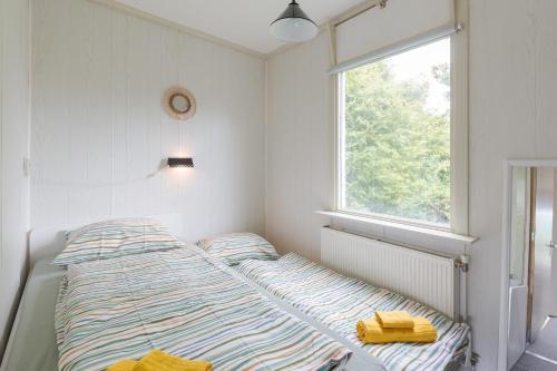 a bed in a white room with a window at NL - Oostmahorn 149 in Anjum