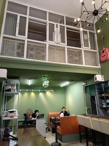 two people sitting at desks in a room with a guitar at Viet Vintage Hostel n Pub - Soft mattress - Free Breakfast in Hanoi