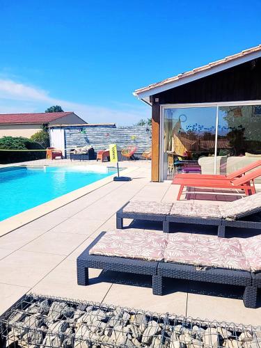 une terrasse avec un lit et une piscine dans l'établissement Chambre Merlot, piscine et spa, proche St Emilion, à Lugon et l’Ile du Carney