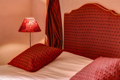 a bed with a red head board with a lamp on it at Château de Castel Novel Boutique Hôtel in Varetz