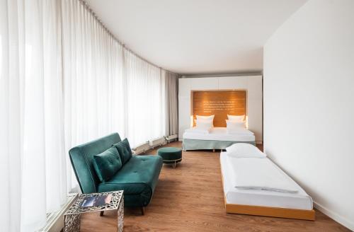 a hotel room with a bed and a green couch at Art Hotel City Leipzig in Leipzig