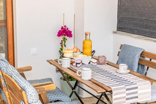 a dining room table with mugs and a vase of flowers at Memory House - The place where your summer story begins in Skála Foúrkas