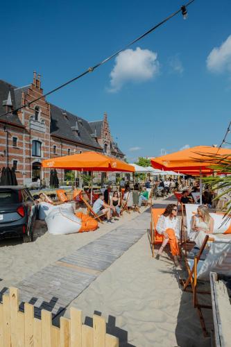a group of people sitting in chairs under orange umbrellas at Van der Valk Hotel Mechelen in Mechelen