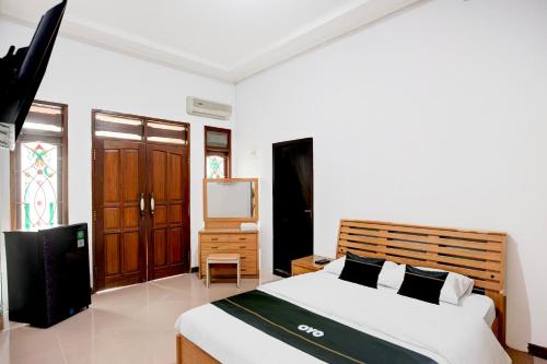 a bedroom with a bed and a television in it at Hotel O Balikpapan near Taman Beruang Madu formerly Palm Cafe Inn in Balikpapan
