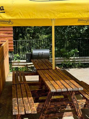 a wooden bench sitting under a yellow umbrella at The Forest Villa Borovets by BookVillaBG in Borovets