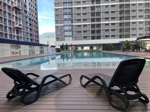 two chairs sitting next to a swimming pool in a building at Pool View Studio - 168 Park Selayang in Batu Caves