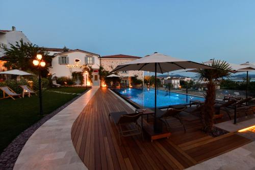 a pool with chairs and an umbrella next to a building at Cunda Ömer Ağa Konağı in Cunda