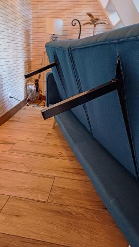 a blue couch sitting on top of a wooden floor at Le Bleu OMER - Jacuzzi & Netflix - Terrasse privée I Coeur de ville & Transports - Idéal FAMILLE - OFFRE SPÉCIALE in Saint-Omer