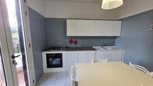 a white kitchen with a table and a sink at la casa nell'acqua in Otranto