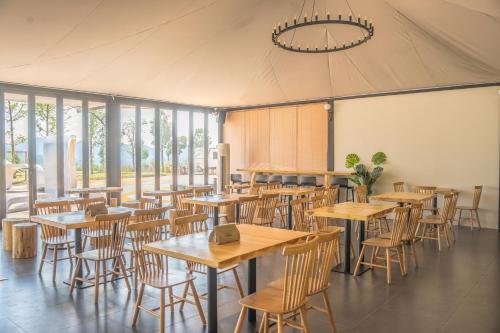 a restaurant with tables and chairs in a tent at Shanyin Xijiang Rustic Luxury Resort Hotel in Bailian