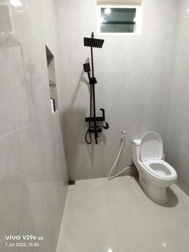 a bathroom with a toilet with a camera on a tripod at Villa Putih O3 in Batu