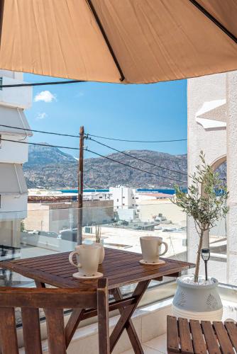a wooden table with two coffee cups on a balcony at Elysian Studios Karpathos in Karpathos Town