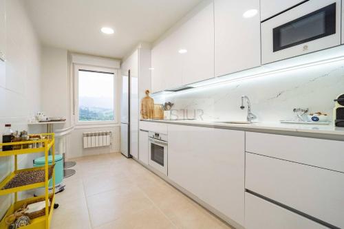 a white kitchen with a sink and a window at Avalón I By Silastur in Villaviciosa