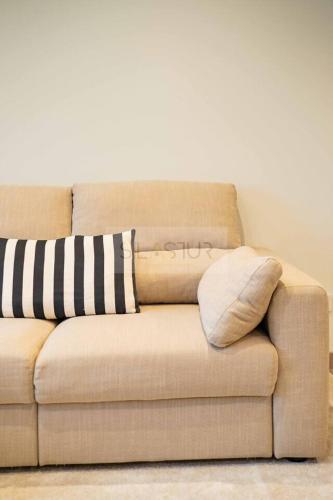 a brown couch with two pillows on it at Avalón I By Silastur in Villaviciosa