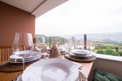 a table with plates and wine glasses on a balcony at Avalón I By Silastur in Villaviciosa