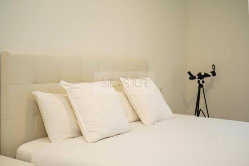 a white bed with white pillows and a camera at Avalón I By Silastur in Villaviciosa