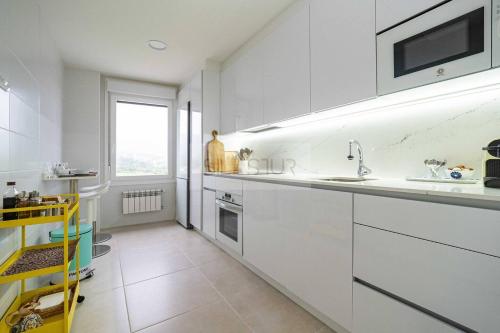 a white kitchen with a sink and a window at Avalón I By Silastur in Villaviciosa