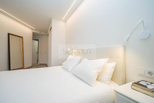 a bedroom with a white bed with white pillows at Avalón I By Silastur in Villaviciosa