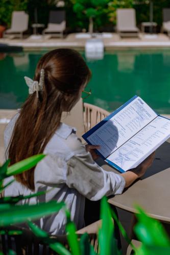 a girl sitting at a table reading a book at Sentimento Sea Breeze in Skala Prinou