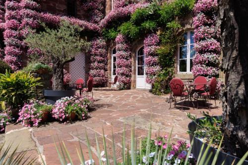 a garden with pink flowers on a building at Château de Castel Novel Boutique Hôtel in Varetz