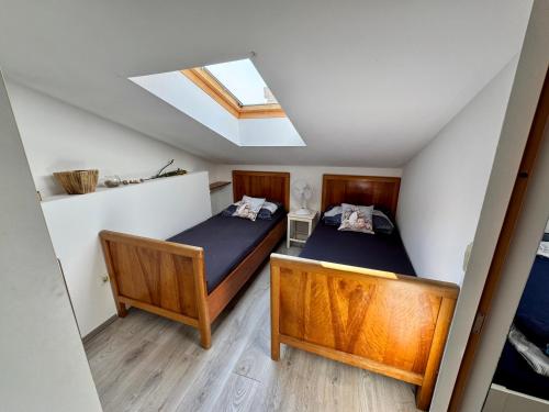 two beds in a small room with a skylight at Sailor apartments in Pag