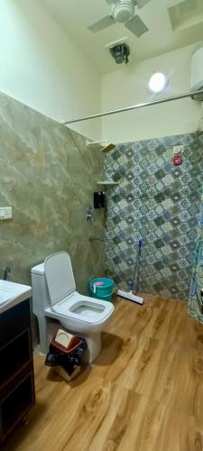 a bathroom with a toilet and a wooden floor at The Hideout Agra - Garden Homestay near Taj in Agra