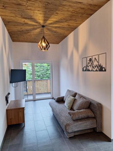 ein Wohnzimmer mit einem Sofa und einer Holzdecke in der Unterkunft Summit View Apartment in Oberperfuss