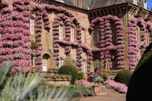 a building with pink flowers on the side of it at Château de Castel Novel Boutique Hôtel in Varetz
