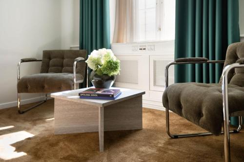 a living room with two chairs and a table with flowers at The Churchill manor apartments by Daniel&Jacob's in Copenhagen