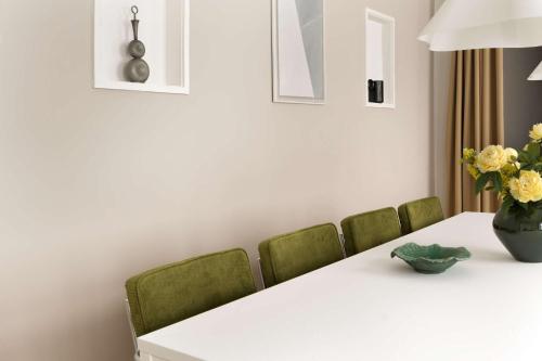 a dining room table with green chairs and a vase of flowers at The Churchill manor apartments by Daniel&Jacob's in Copenhagen
