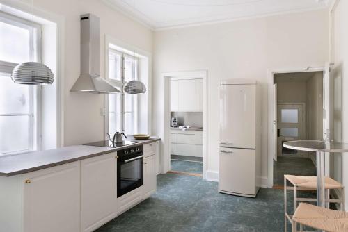 a white kitchen with a refrigerator and a table at The Churchill manor apartments by Daniel&Jacob's in Copenhagen