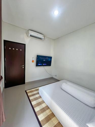 a small room with a bed and a tv at Rumah Mungil Nyaman in Muara