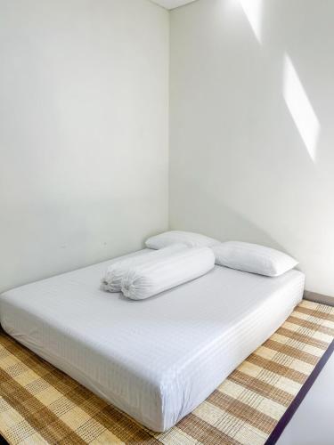 a bed with white sheets and pillows in a room at Rumah Mungil Nyaman in Muara