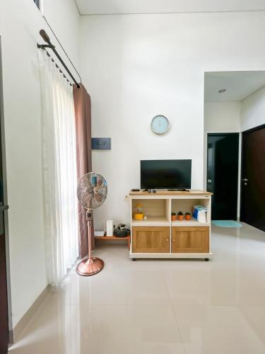 a living room with a television and a fan at Rumah Mungil Nyaman in Muara