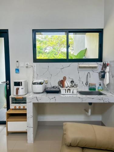 a kitchen with a counter with a sink and a window at Rumah Mungil Nyaman in Muara