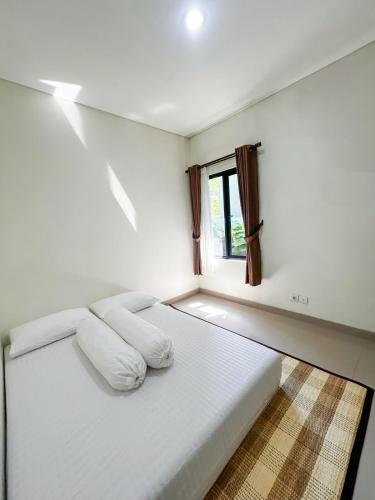 a white bed in a room with a window at Rumah Mungil Nyaman in Muara